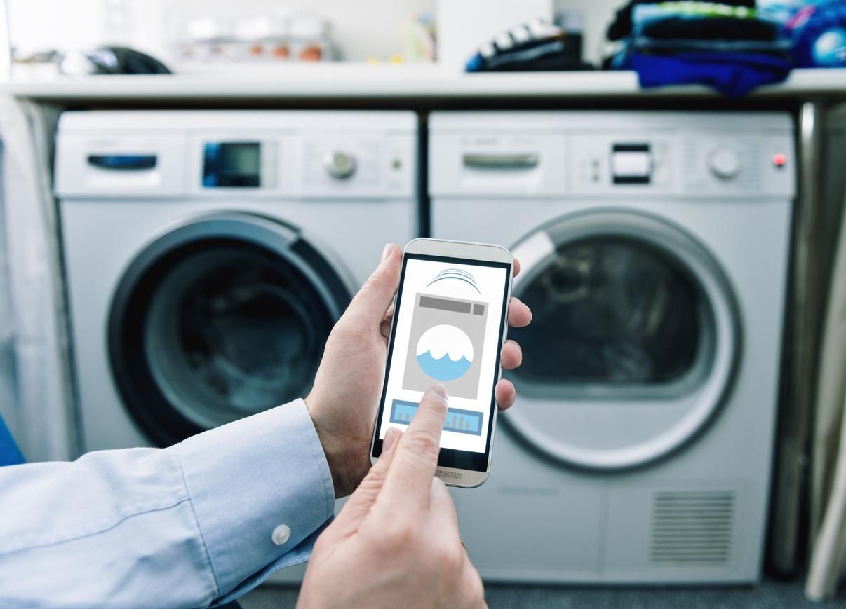 a photo of a smartphone with app controlling washing machine and dryer.
