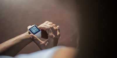 a photo of a woman taking her heart rate on a smartwatch