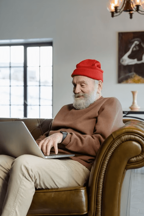 photo of an elderly man sitting in a chair on a laptop