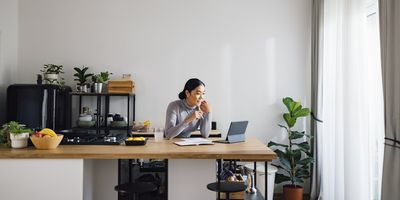 a photo of a woman sitting behind a desk on her laptop in her home office.