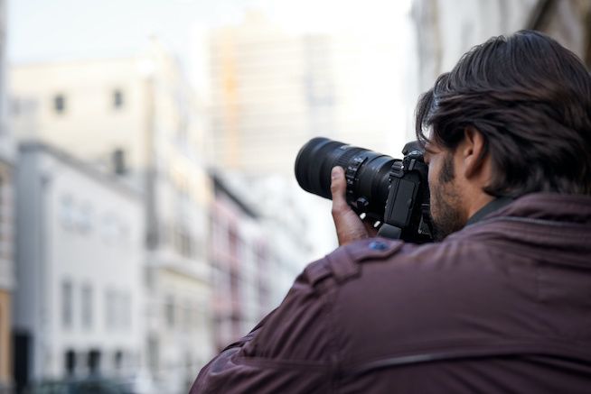 Someone holding a camera up to their eye and photographing a city scape