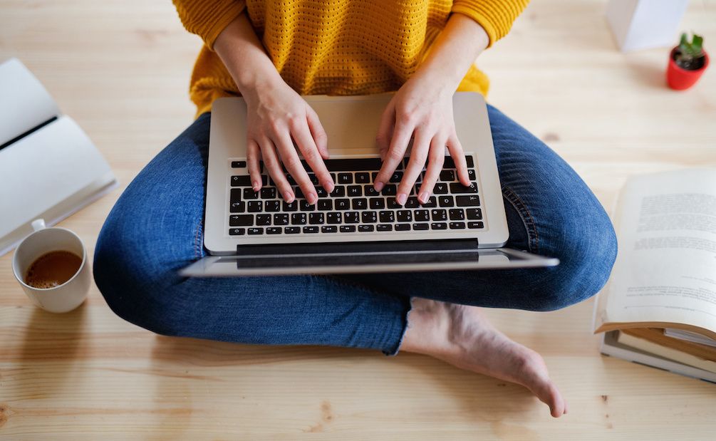 A student seated on the floor with a laptop computer