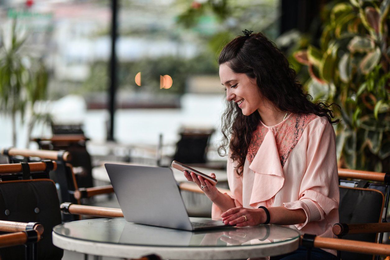 a woman using her smartphone and tablet at a coffee shop