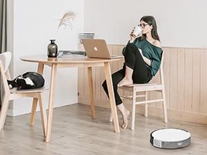 a photo of a woman in a kitchen with Tapo RV10 Lite robot vacuum on the floor cleaning.