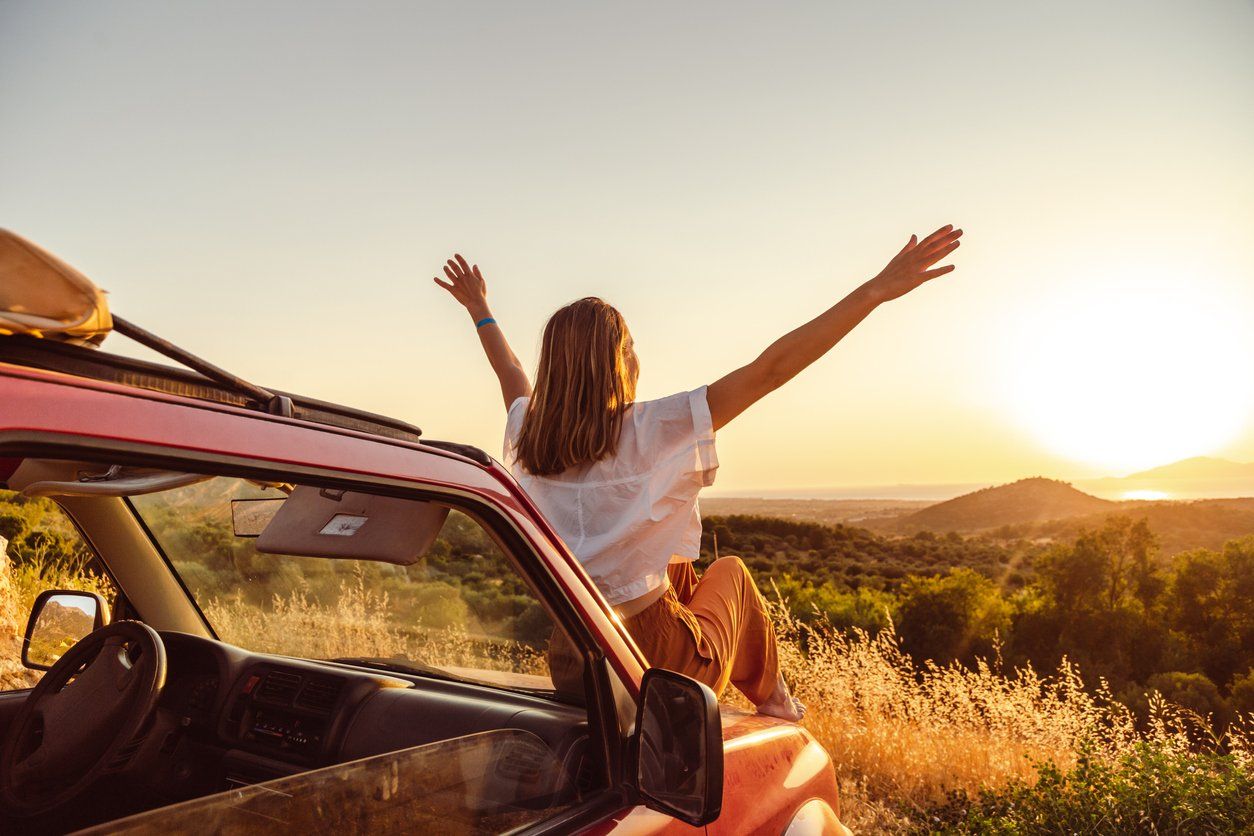 a photo of a woman on a car watching the sunset