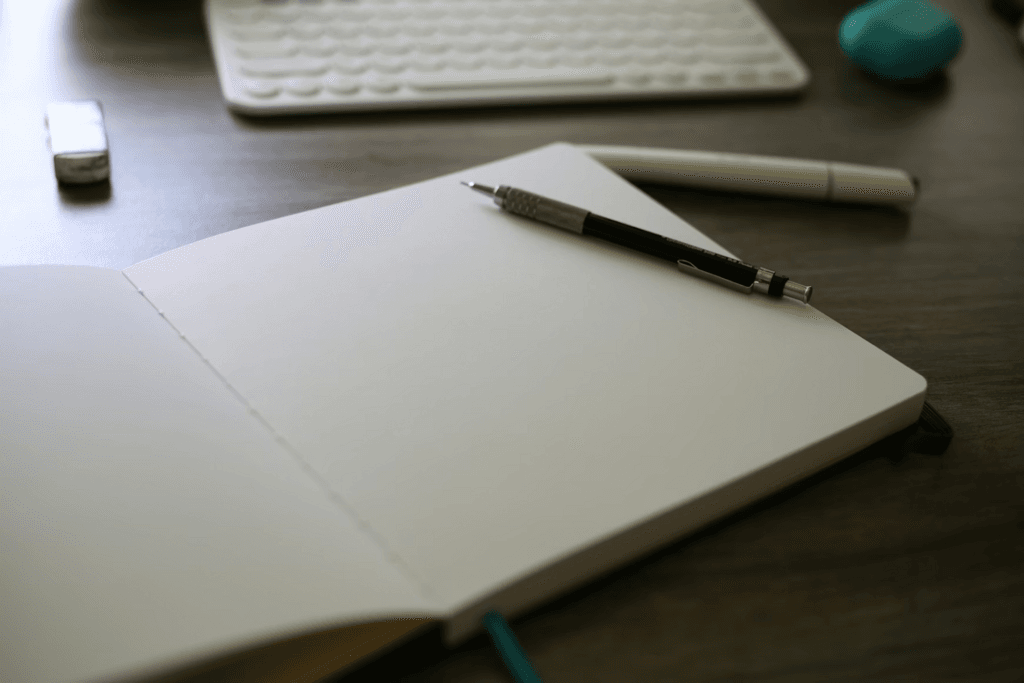 photo of a notebook with pen and laptop on a desk