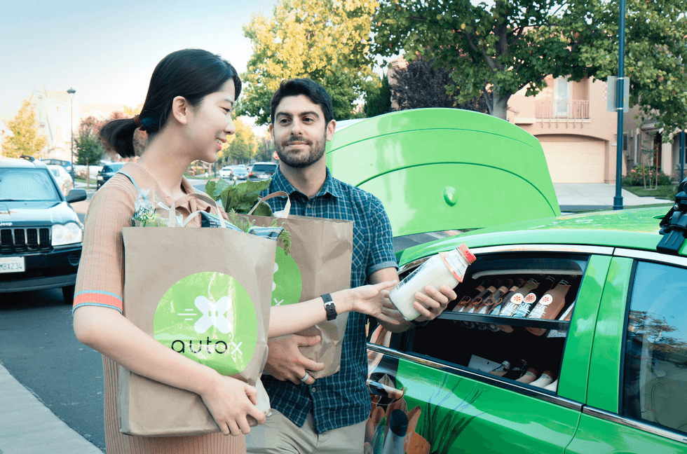man and woman carrying groceries to a car.