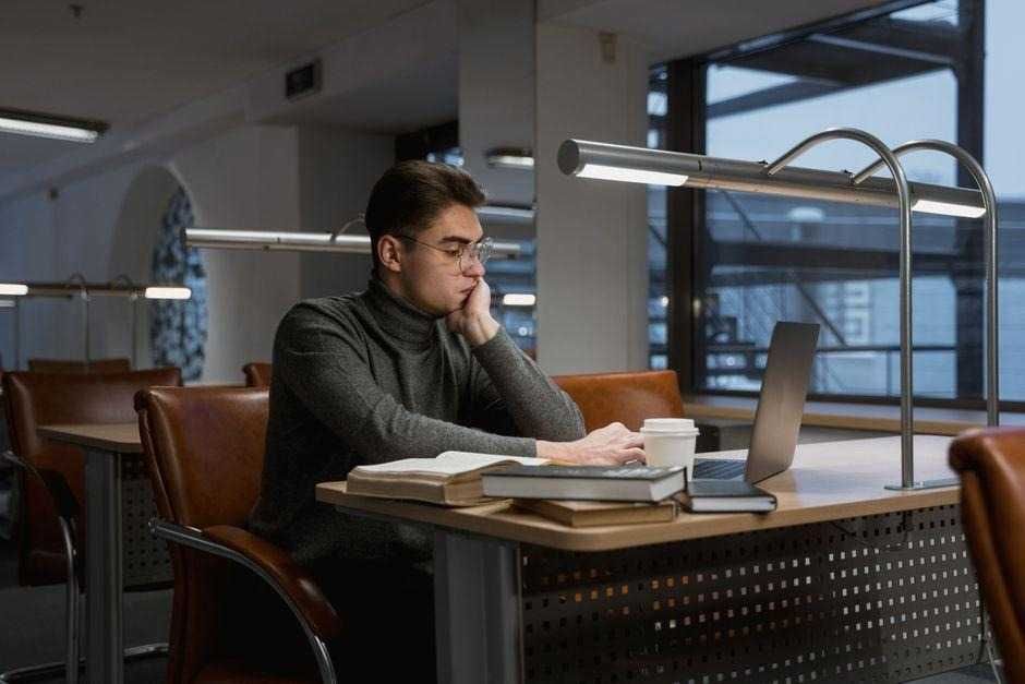 a photo of a man studying in a library