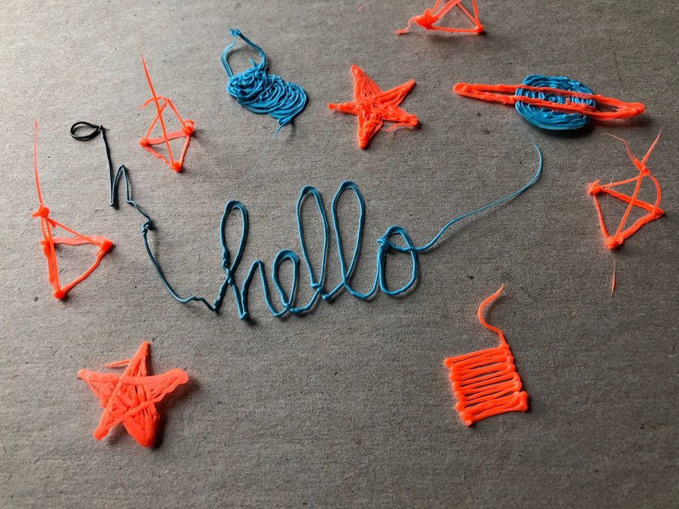 Orange and blue objects that look like sketches in plastic, including the word draw in blue, 'hello' in script