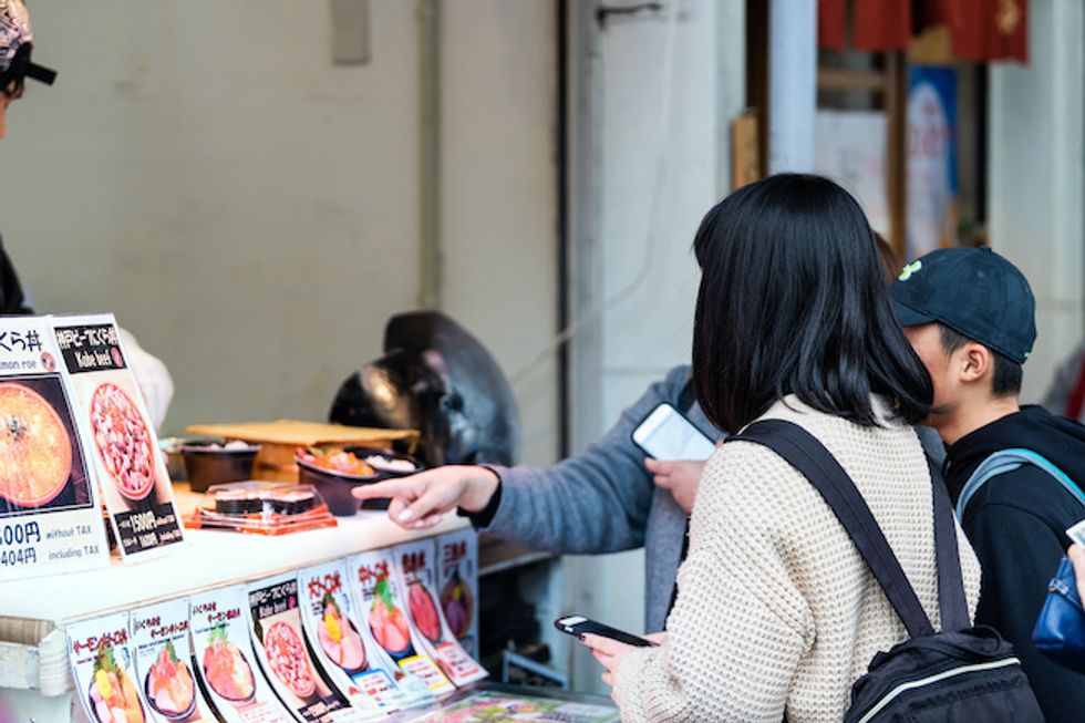 People buying food on street in Tsukiji near Ginza with Kobe beef meat food vendor menu