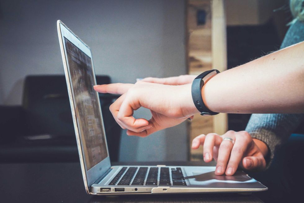 persons pointing to a laptop screen