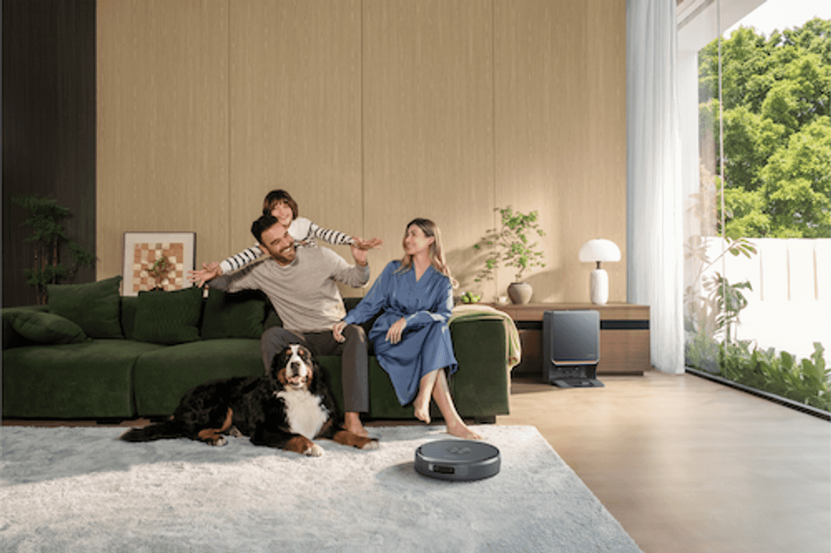 photo of a family sitting on a couch with Narwal robot vacuum cleaning the rug