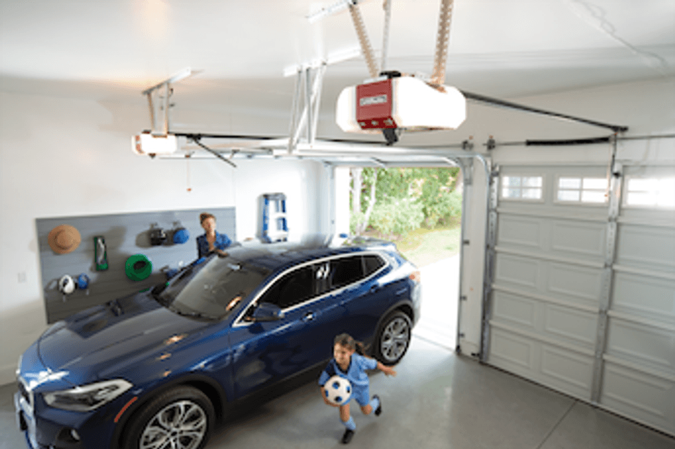 photo of a garage with a car in it and a child running with a soccer ball