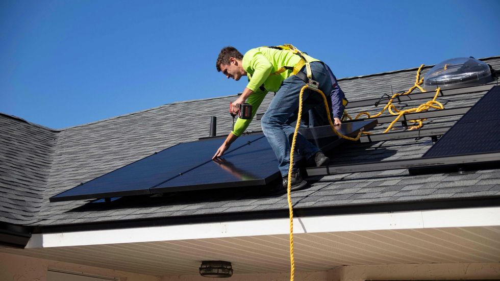 photo of a man on the roof installing solar panel
