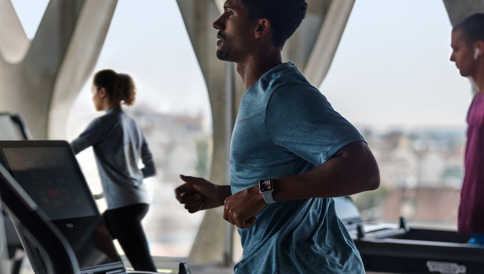 Photo of a man running on a treadmill and wearing an Apple Watch