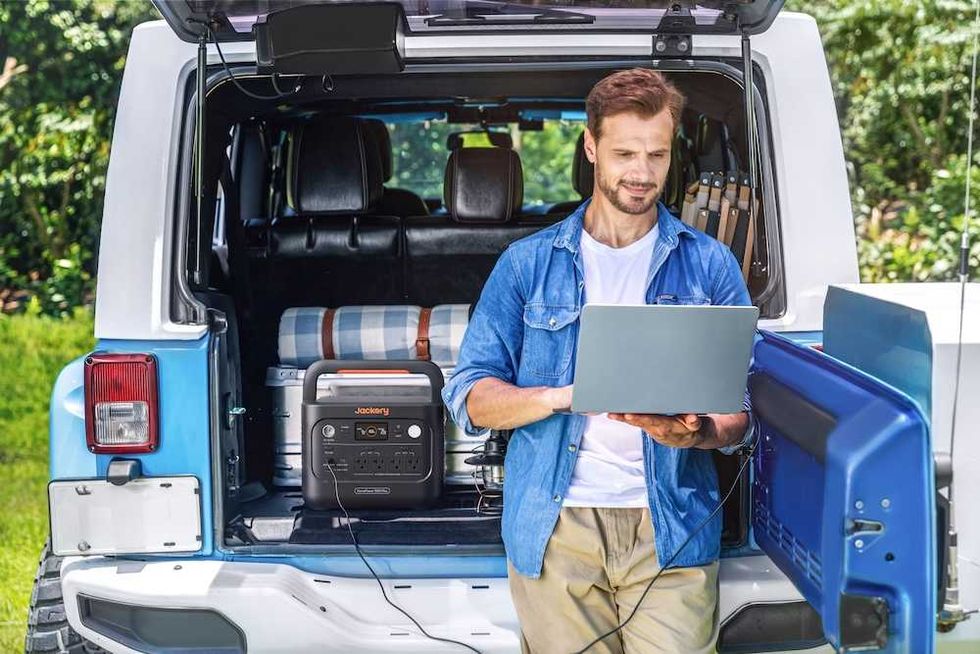 Photo of a man working on his laptob connected to HomePower 1000 Plus V2.