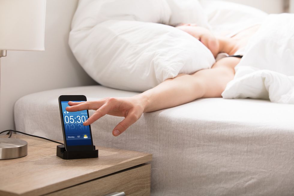 photo of a smartphone beinig used as a alarm clock on a nightstand.