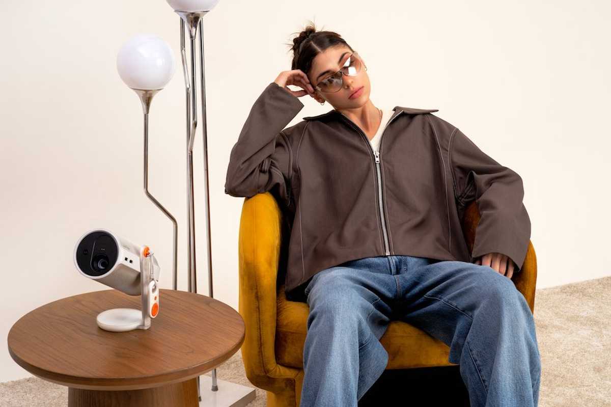 photo of a woman sitting in a chair with Xgimi MoGo 4 portable projector on a table.