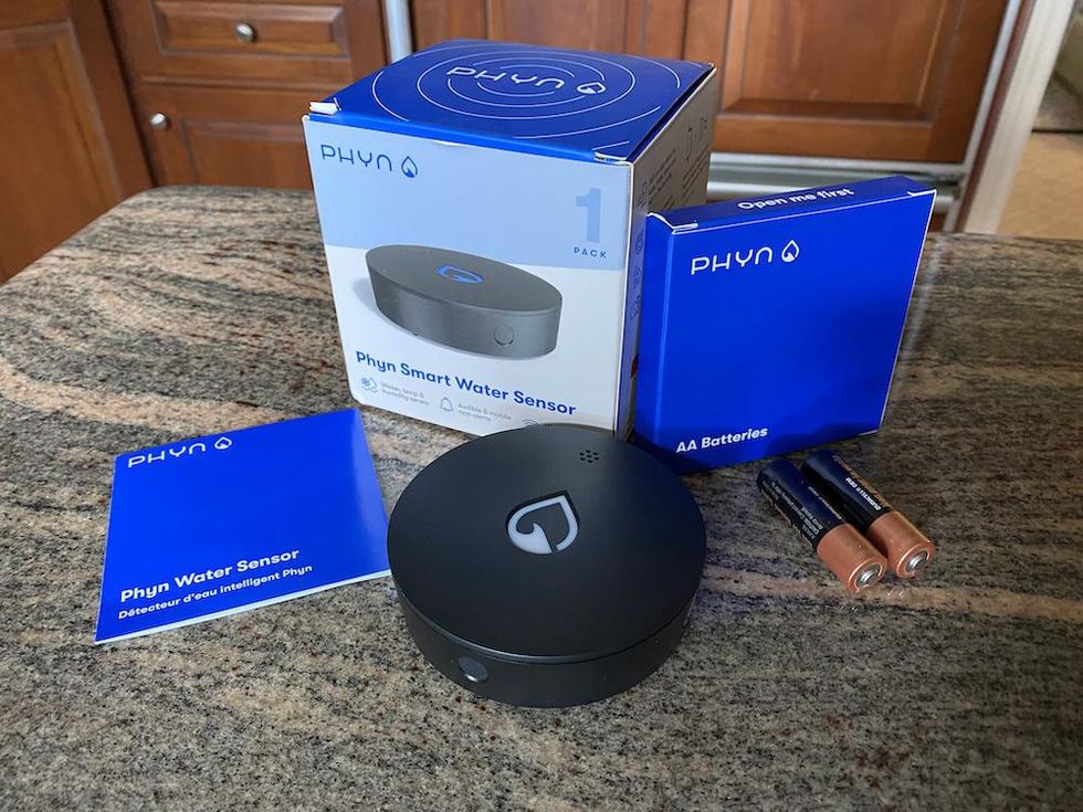 Phyn Smart Water Sensor unboxed on a counter.