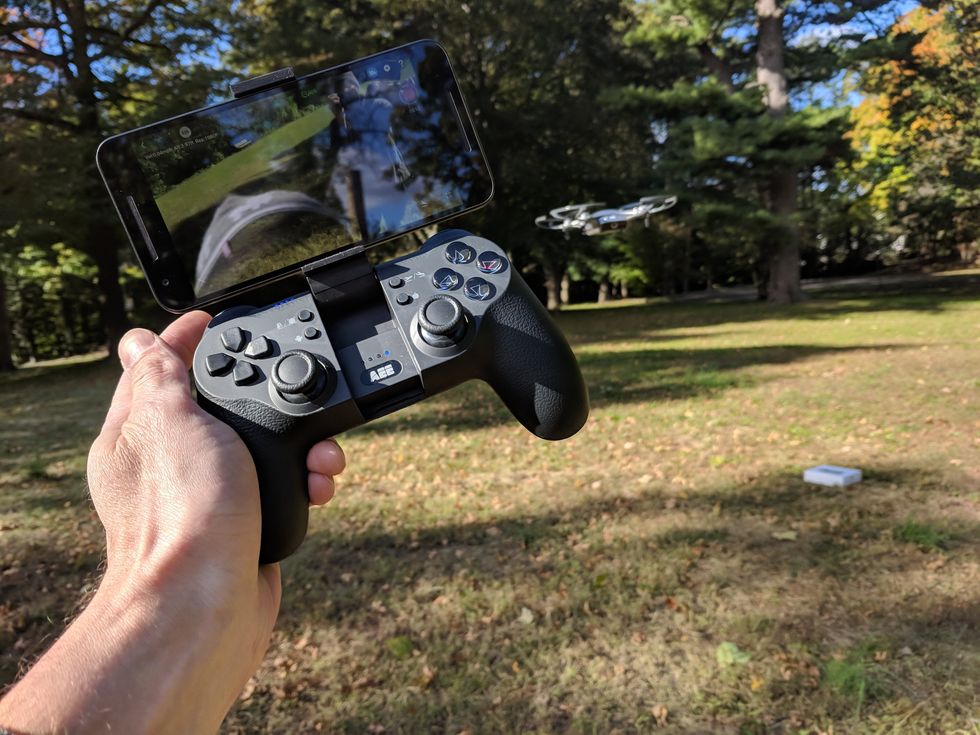 Picture of AEE Mach 1 Drone controller outiside with smartphone attached and flying Mach 1 drone.