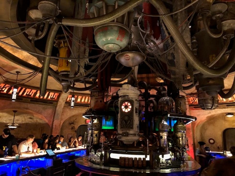 Pipes and hoses drape down to a center bar lit with red, blue and green lights