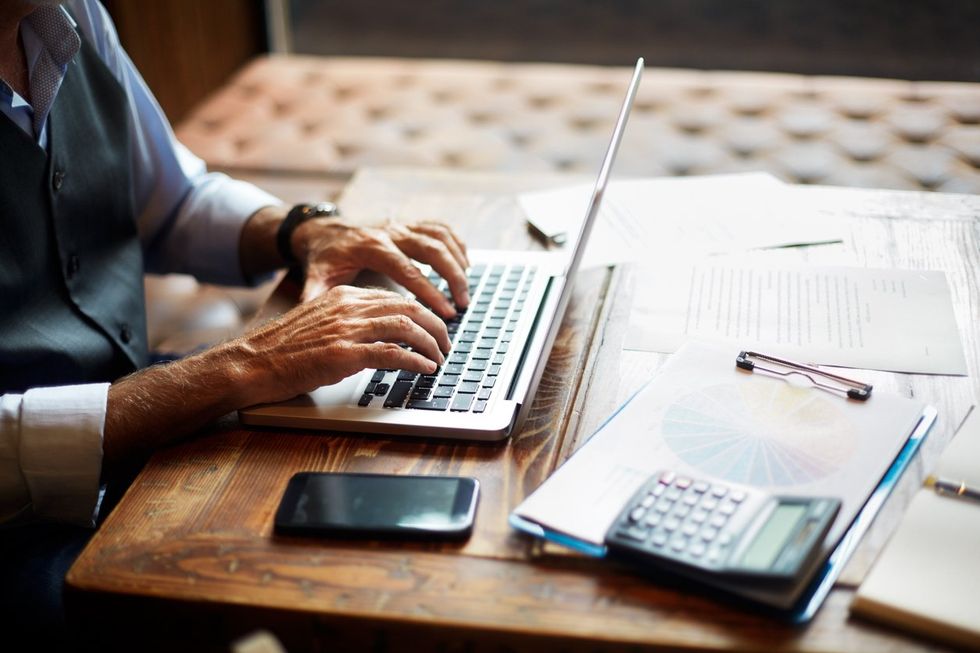 Senior businessman typing on a laptop in a coworking space stock photo