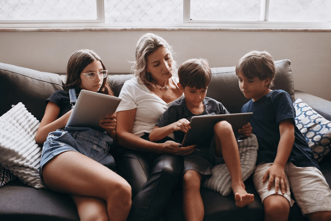 a photo of a mom and three children reading together on a couch