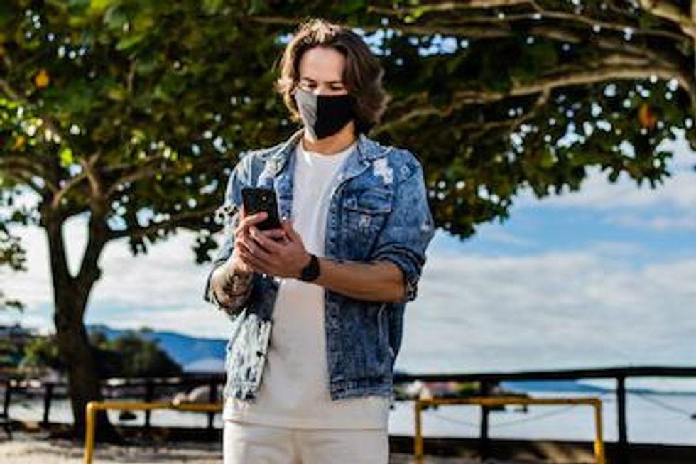 Someone wearing a mask and holding a mobile phone
