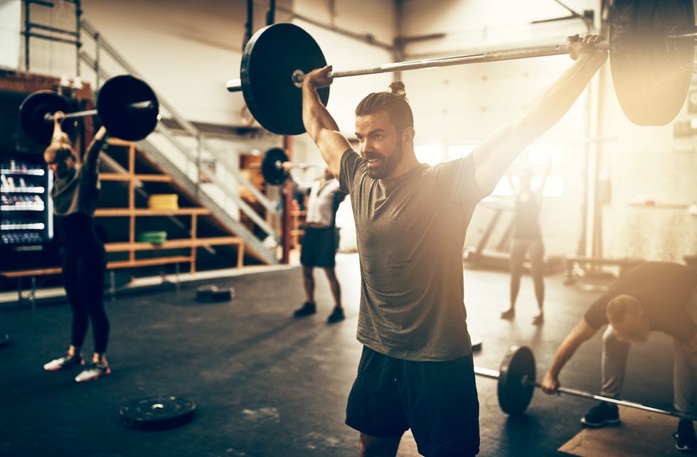 Stock image of man listing weights in the gym