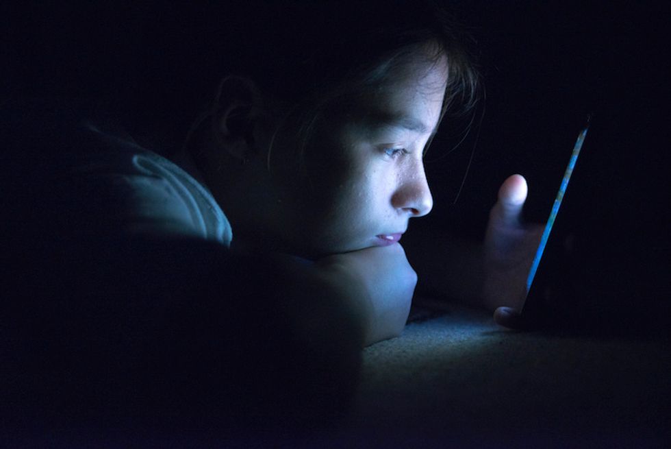 Teenager sending email from smart phone in her bed