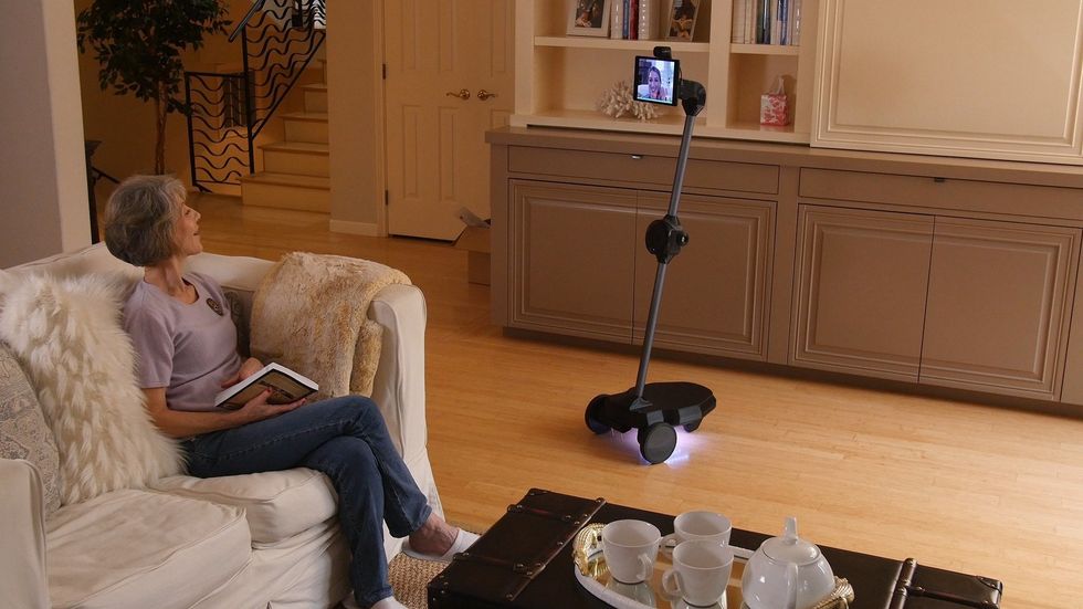 The Ohmni Robot in a home in front of a woman seated on a couch
