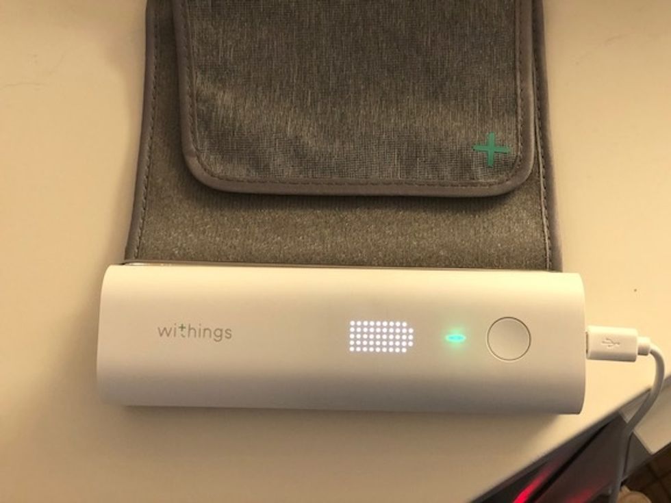 The Withings white monitor showing a green light and a white battery symbol