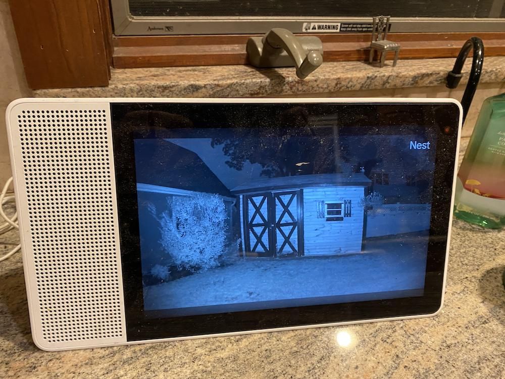 A google assistant smart display showing live video from Google Nest Cam at night time.