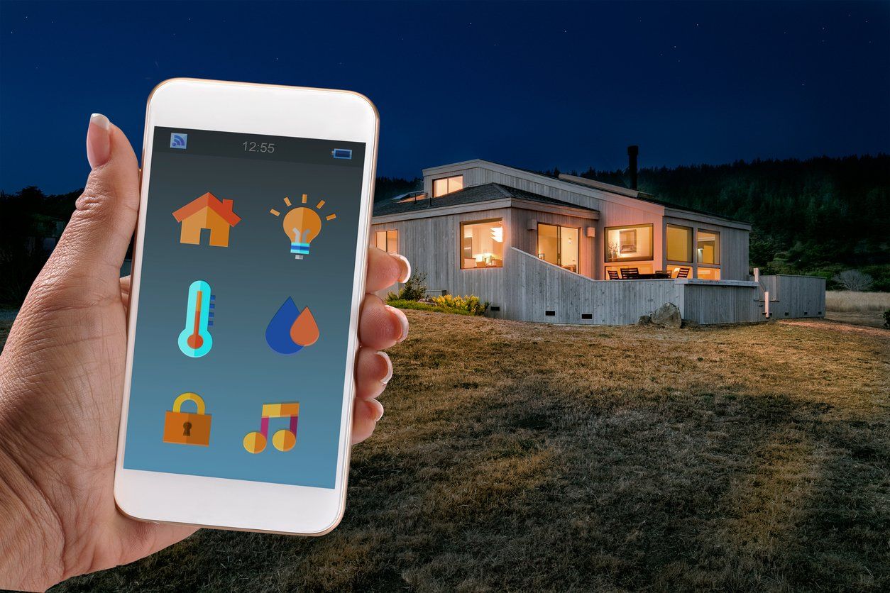Home Automation: Woman holding Smart Home app with smart phone at night in front of house, concept for home automation stock photo