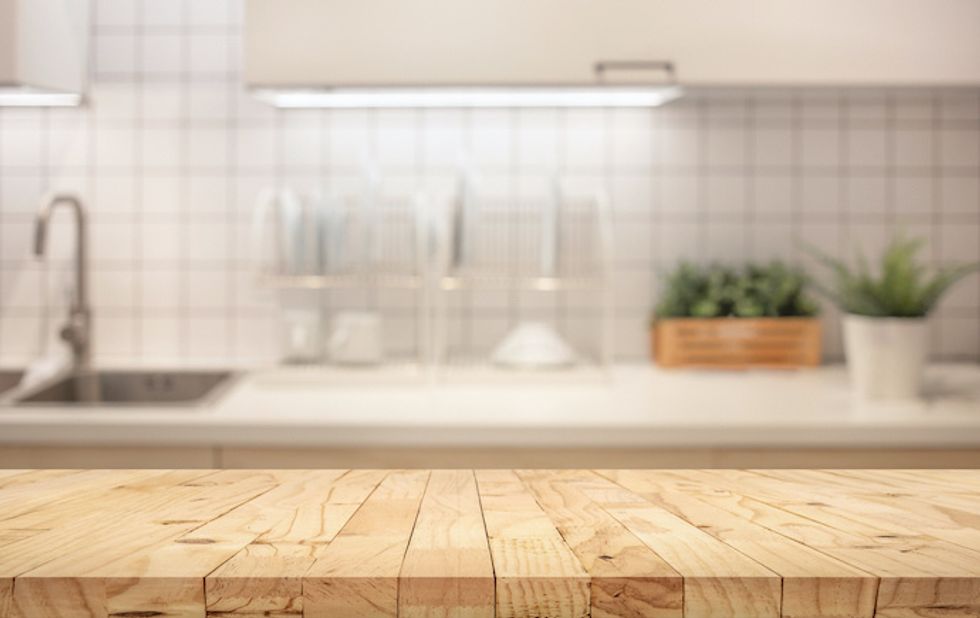 Wood table top on blur kitchen counter (room)background.